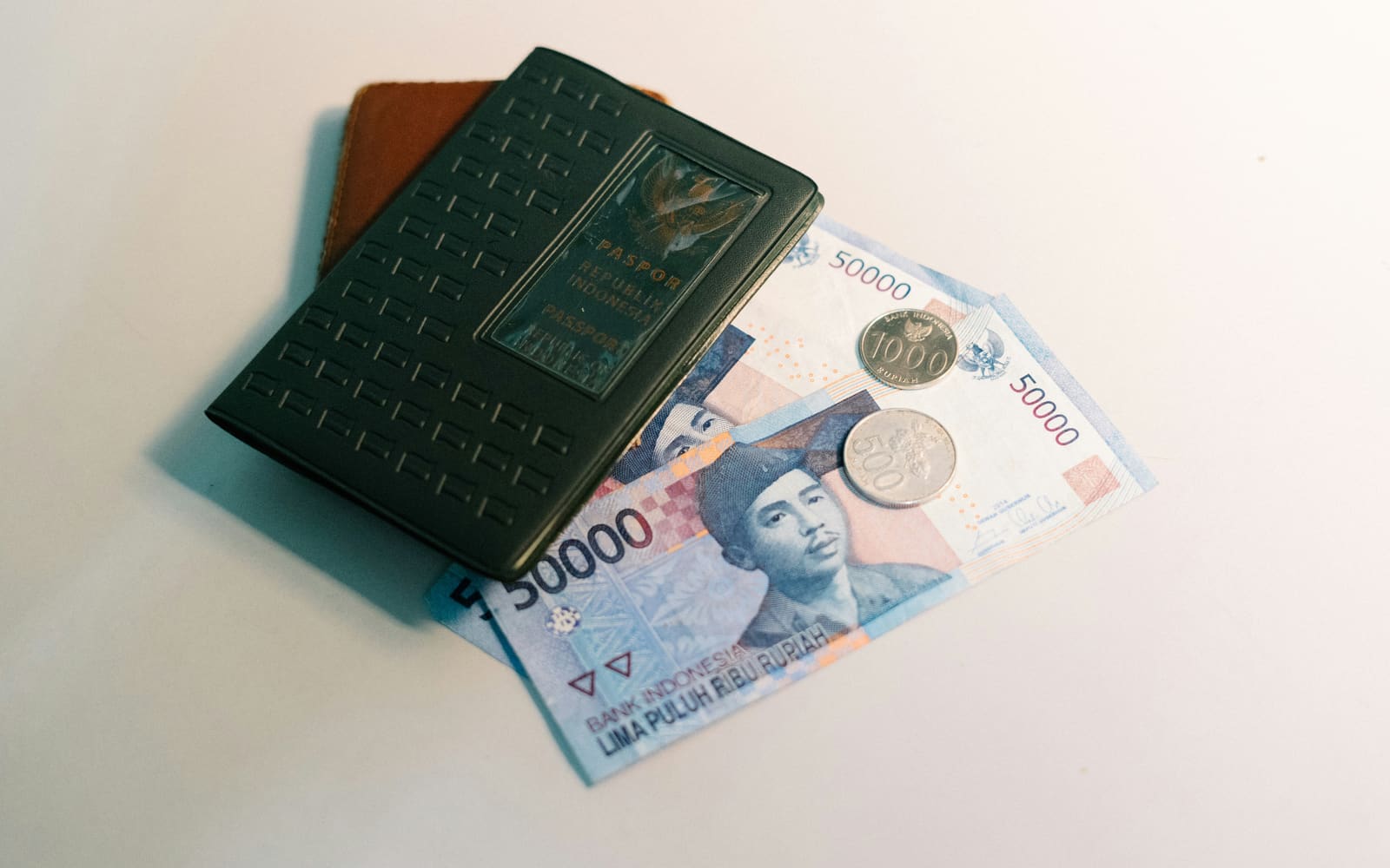 A passport and wallet on top of foreign banknotes and coins