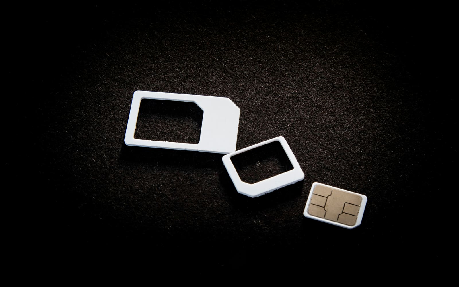 SIM cards in standard, micro and nano sizes on a black surface